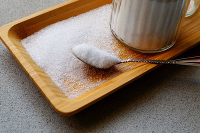 a teaspoon of sugar overflowing onto a wooden tray